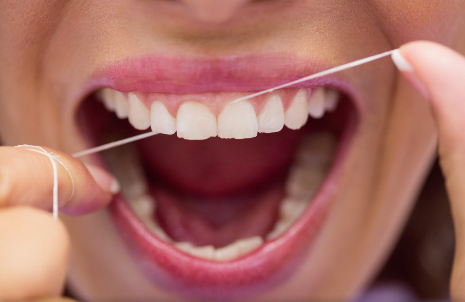 Close-up of person flossing teeth for daily oral hygiene